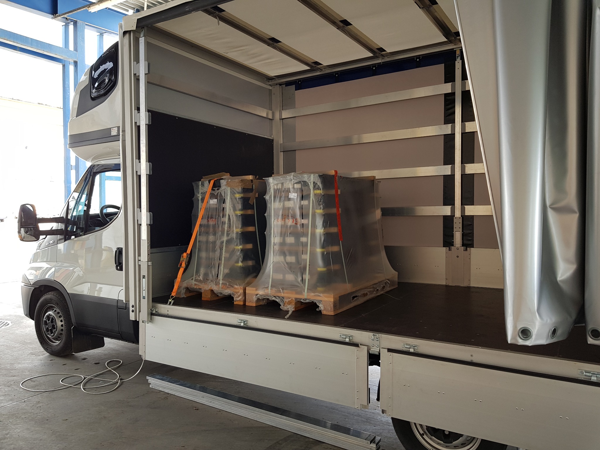 Załadunek dwóch palet z towarem zabezpieczonych folią i pasami transportowymi wewnątrz przestrzeni ładunkowej busa w Piasecznie.