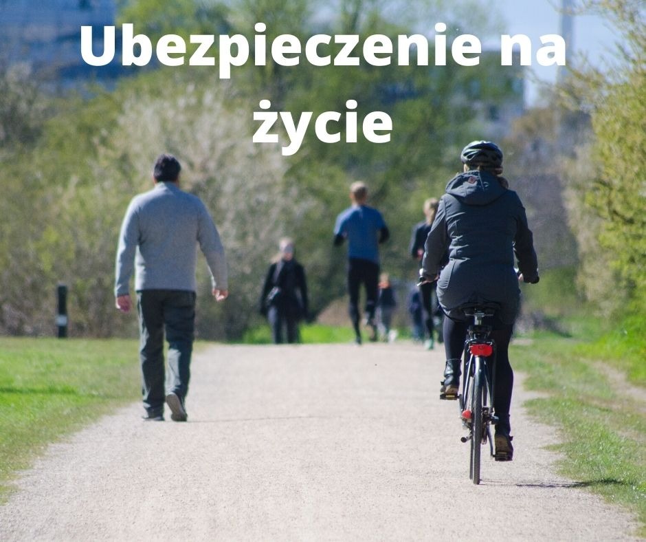 Osoba na rowerze jedzie ścieżką w parku, w tle spacerujący i biegający ludzie w słoneczny dzień.