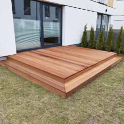 Dwupoziomowy taras z drewna egzotycznego, przylegający do nowoczesnego domu z dużym oknem tarasowym i rzędem małych drzew iglastych w tle.