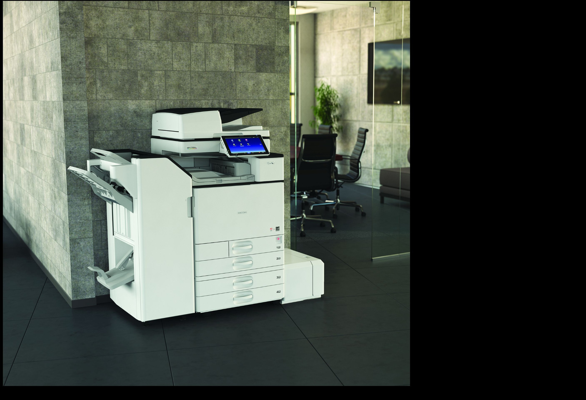 Nowoczesna, biała kserokopiarka wielkoformatowa Ricoh z panelem dotykowym, umieszczona w biurze z szarą ścianą z płytek i przeszklonym pomieszczeniem w tle.