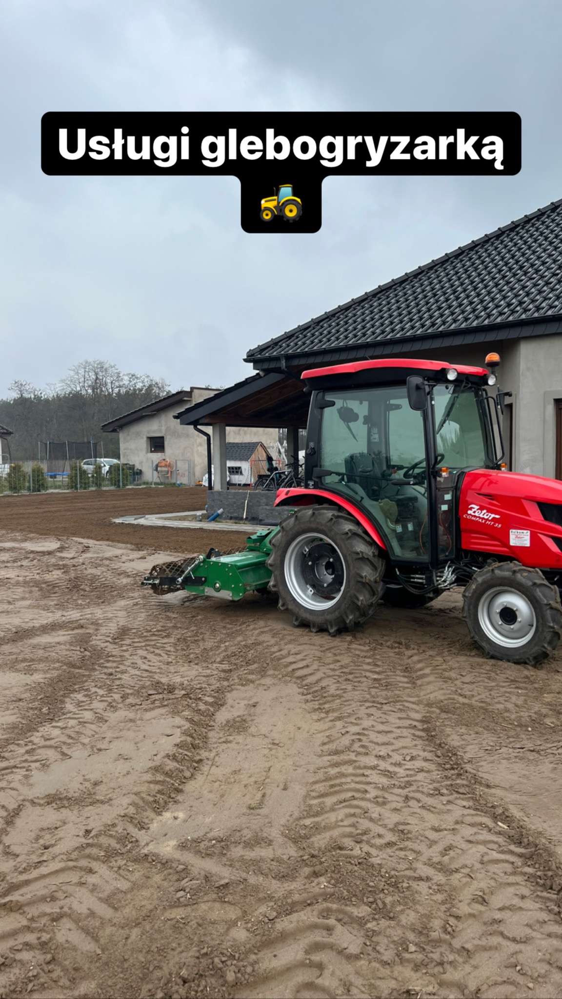 Czerwony traktor Zetor Compax HT 35 z glebogryzarką separacyjną na polu uprawnym przed domem. Widoczne ślady opon na ziemi.