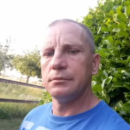 Portret mężczyzny z Środy Wielkopolskiej na tle zieleni, być może pracownika firmy budowlanej.