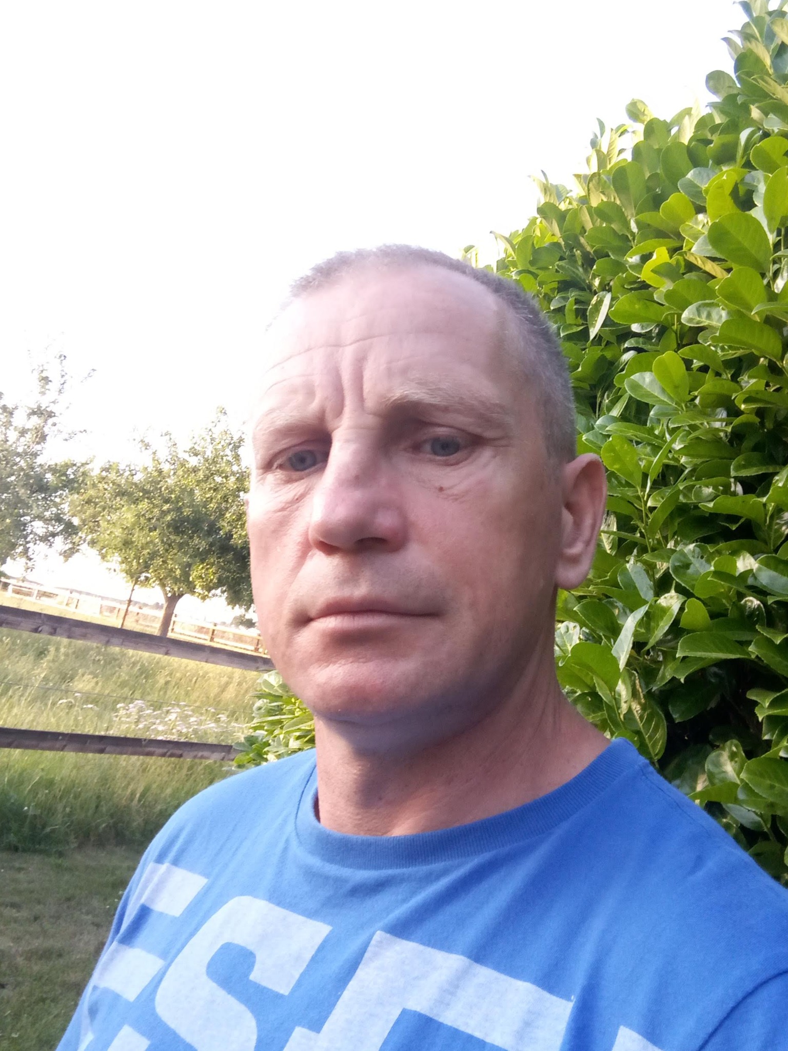 Portret mężczyzny z Środy Wielkopolskiej na tle zieleni, być może pracownika firmy budowlanej.