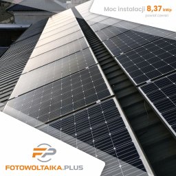 Fotowoltaika Plus - Instalacja paneli słonecznych na dachu z blachy, widoczny napis 'Moc instalacji 8,37 kWp powiat czerski' oraz logo firmy 'Fotowoltaika.plus'.