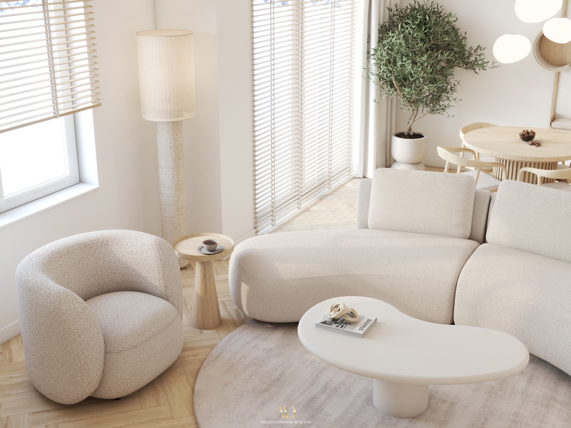 Jasne wnętrze z beżową sofą modułową, okrągłym stolikiem kawowym z książką 'Bauhaus', fotel typu boucle, drewniany stolik pomocniczy z filiżanką, lampa podłogowa z abażurem z tkaniny i drzewko...