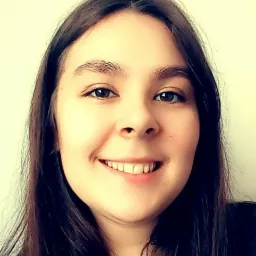 Portret uśmiechniętej kobiety z długimi, ciemnymi włosami na jasnym tle.