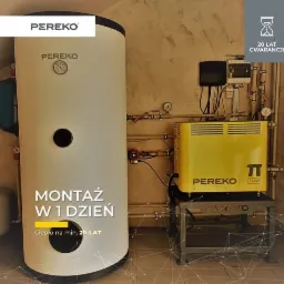 Kocioł indukcyjny Pereko z pionowym zasobnikiem, widoczny na tle ściany z instalacją hydrauliczną i sterownikiem, z naklejką informującą o 20-letniej gwarancji.