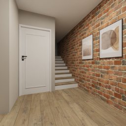 OLIV - Design projektowanie wnętrz Justyna Leszczyńska - Korytarz z ceglaną ścianą, zdobiony abstrakcyjnymi obrazami w białych ramach. Widoczne schody i drzwi, a w tle fragment salonu z kominkiem.