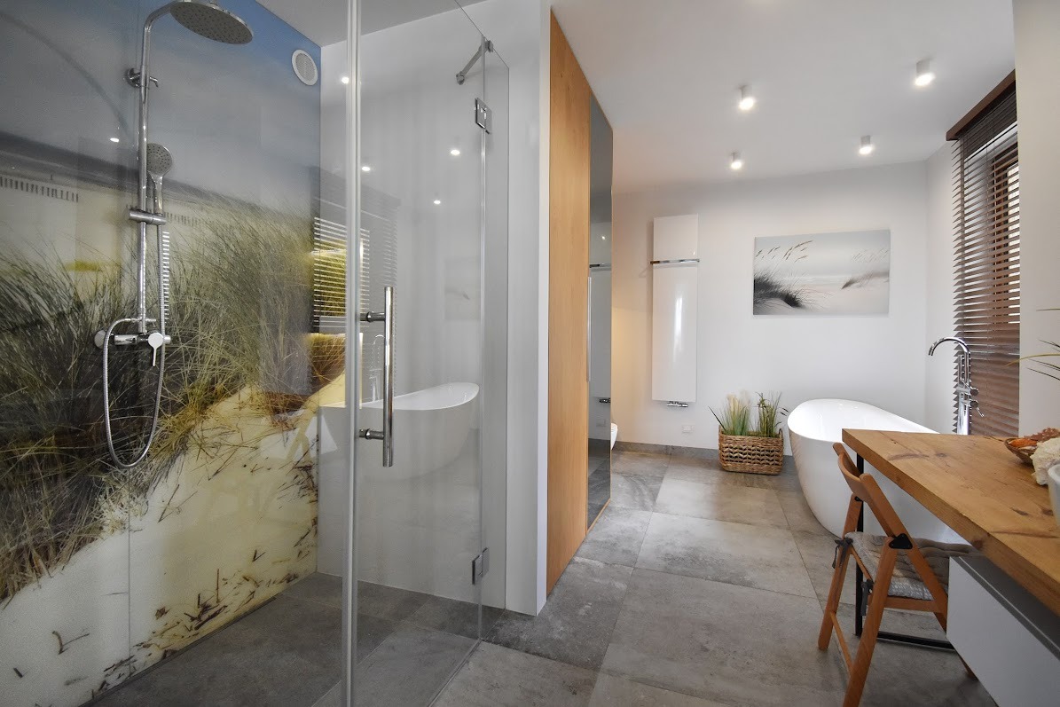 Nowoczesna łazienka z kabiną prysznicową z fototapetą przedstawiającą nadmorski krajobraz, wolnostojąca wanna i drewniany blat.