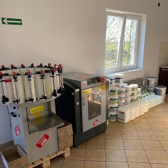 Maszyna do mieszania farb z pojemnikami pigmentów i rzędem gotowych puszek z farbą przy ścianie z oknem.