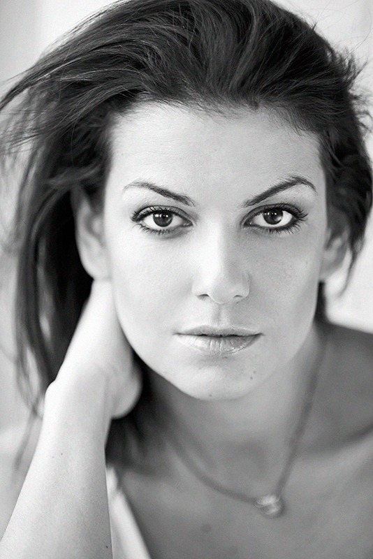 Portret kobiety z delikatnym błyszczykiem na ustach i subtelnym podkreśleniem oczu, czarno-białe zdjęcie.