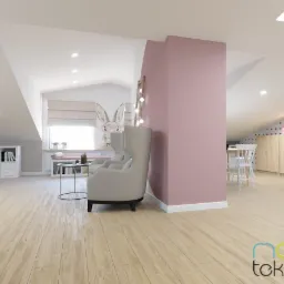 Jasne poddasze z drewnianą podłogą, beżowy fotel uszak, okrągły stolik, białe meble na ścianie, huśtawka wisząca i różowa ściana.