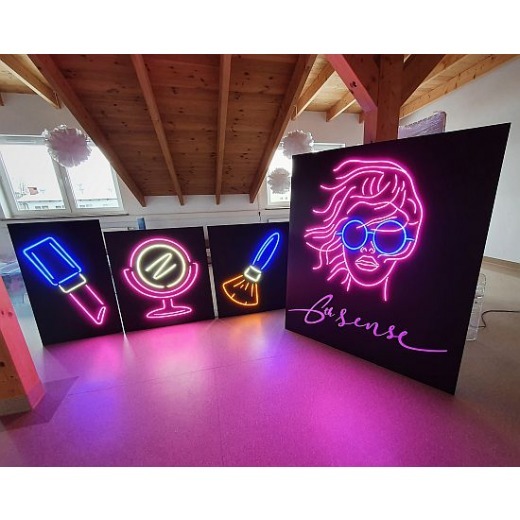 Cztery podświetlane panele z neonowymi grafikami: szminka, lusterko, pędzel do makijażu i portret kobiety w okularach z napisem 'Busense'.