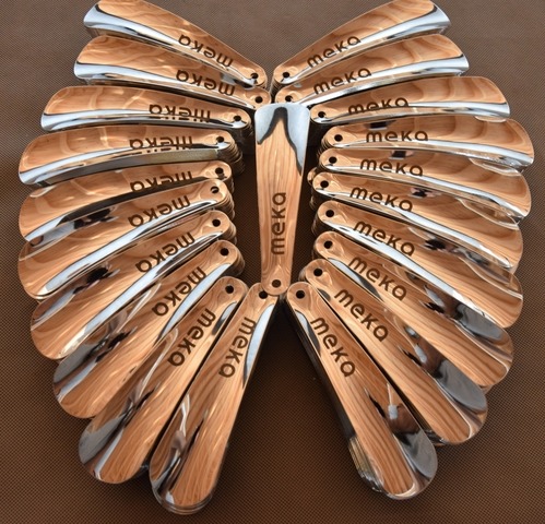 Partia metalowo-drewnianych łyżek do butów z wygrawerowanym logo 'meka', ułożonych promieniście na brązowym tle.