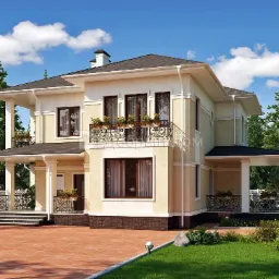 Dwukondygnacyjny dom z beżową elewacją, ciemnym dachem, kolumnami przy wejściu i balkonach z ozdobnymi balustradami, otoczony zielenią.