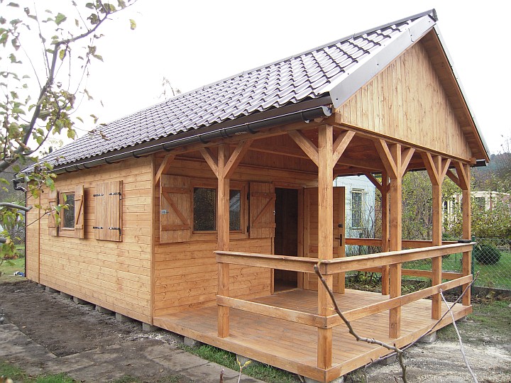 Gotowa altana z drewna z zadaszonym tarasem, brązowe okiennice i dachówka, widok z zewnątrz.