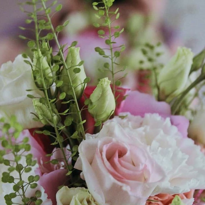 Delikatny bukiet z różowych i białych róż, goździków i zielonych pąków, ujęcie z bliska, miękkie światło.