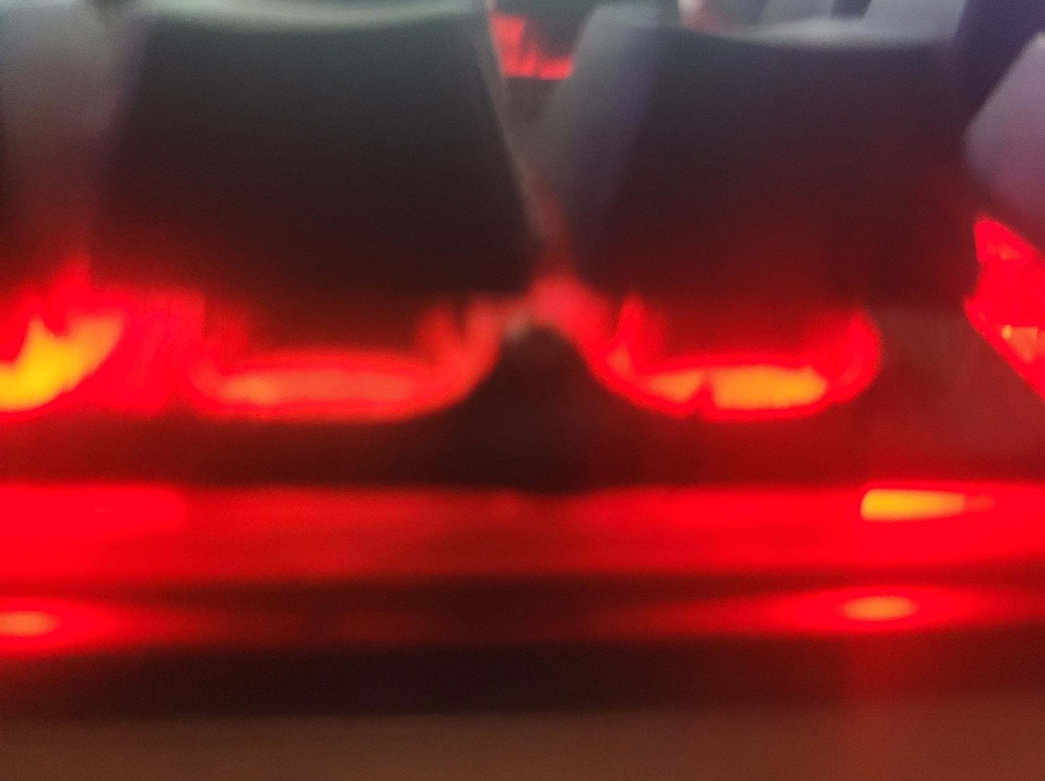 Podświetlana klawiatura mechaniczna z czerwonymi diodami LED, widok z bliska, lekko rozmazany obraz.