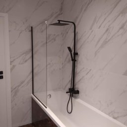 Kamil susel - Nowoczesna łazienka z białą wanną, czarną armaturą i szklanym parawanem, ściany wyłożone płytkami imitującymi marmur.