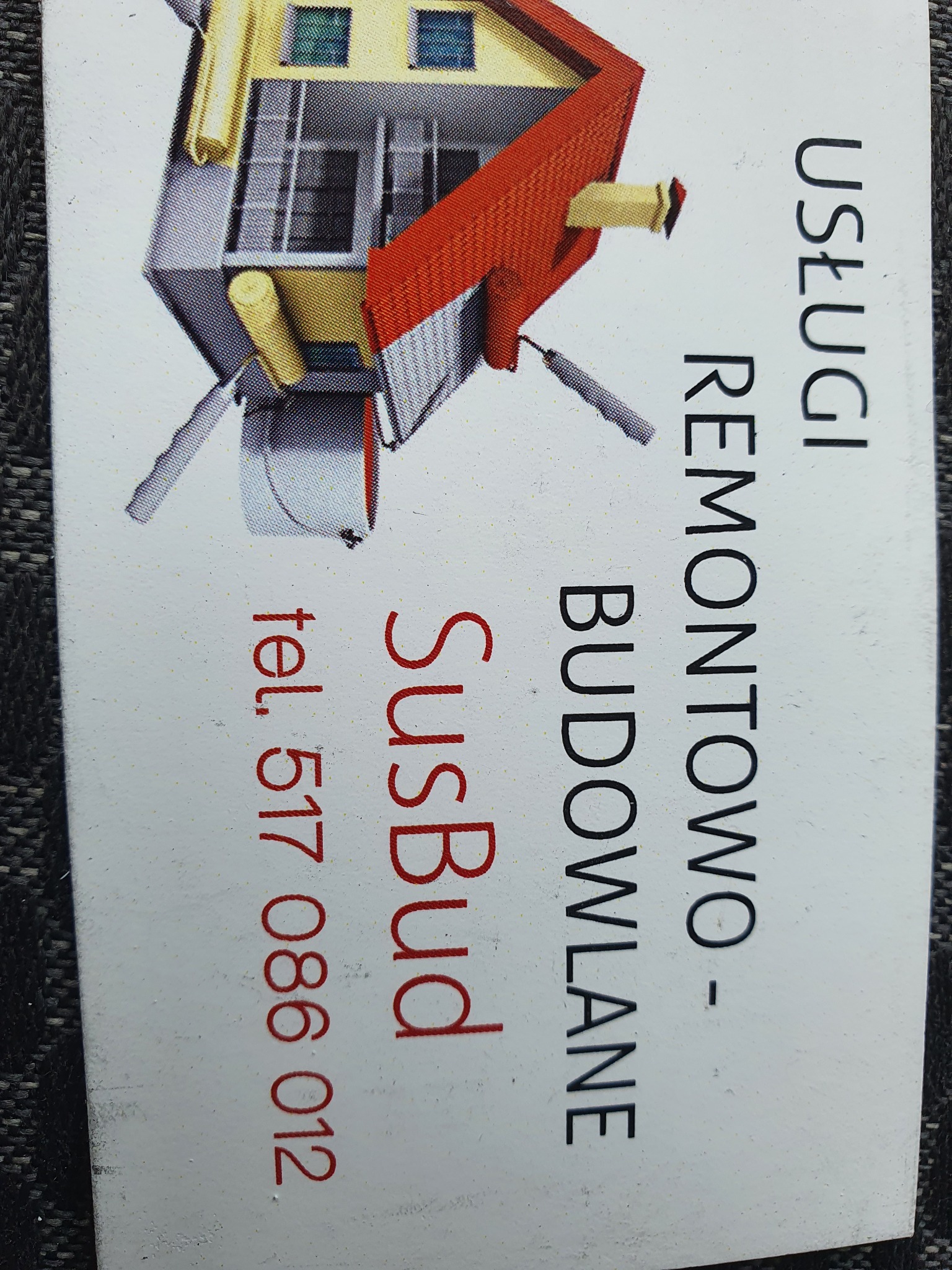 Wizytówka firmy budowlanej SusBud z graficznym przedstawieniem domu malowanego wałkami, obok pionowo wypisane: Usługi Remontowo-Budowlane, poniżej numer telefonu 517 086 012.