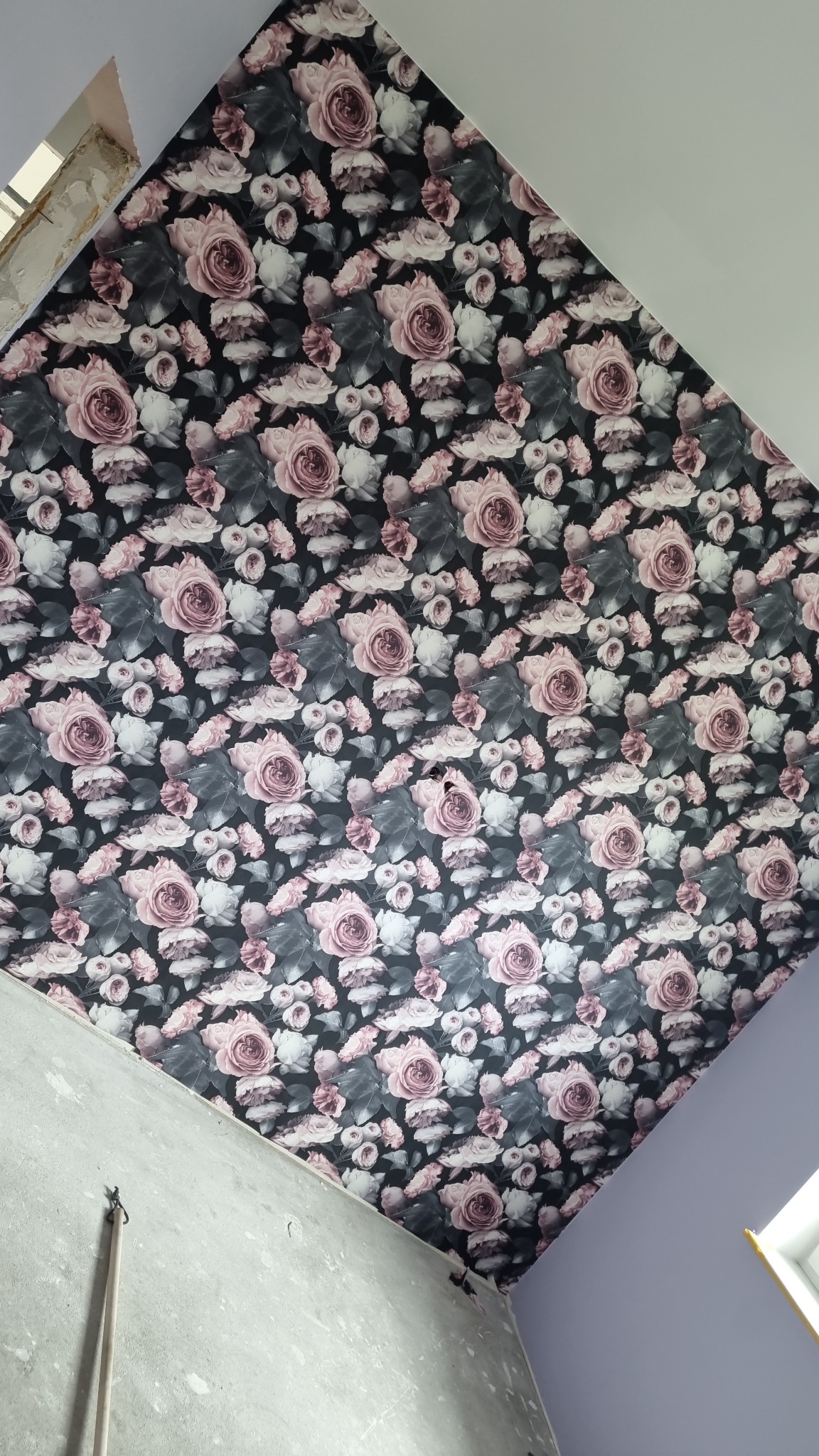 Wzorzysta tapeta w różowe róże na suficie, widok z dołu, surowe wykończenie ścian w tle.