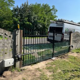 KLIMERA Michał Garbiec - Czarna, metalowa brama wjazdowa z zamontowaną automatyką, widoczna skrzynka sterująca i siłownik. W tle zaparkowany biały bus z drabiną na dachu.