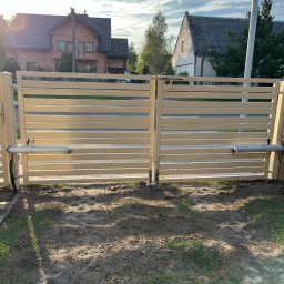 KLIMERA Michał Garbiec - Automatyczna brama posesyjna z poziomymi panelami w kolorze beżowym, z widocznymi siłownikami, na tle domów jednorodzinnych w słoneczny dzień.