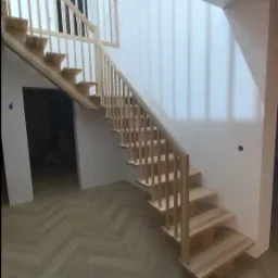 Schody jesionowe na belce z drewnianą balustradą.