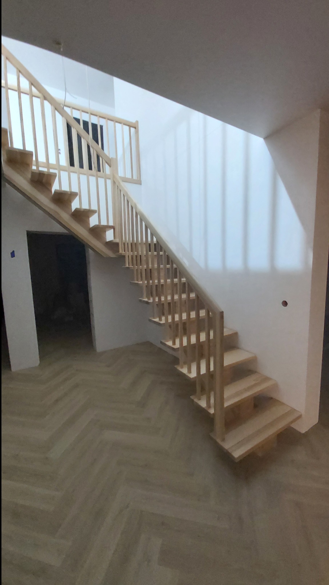 Schody jesionowe na belce z drewnianą balustradą.