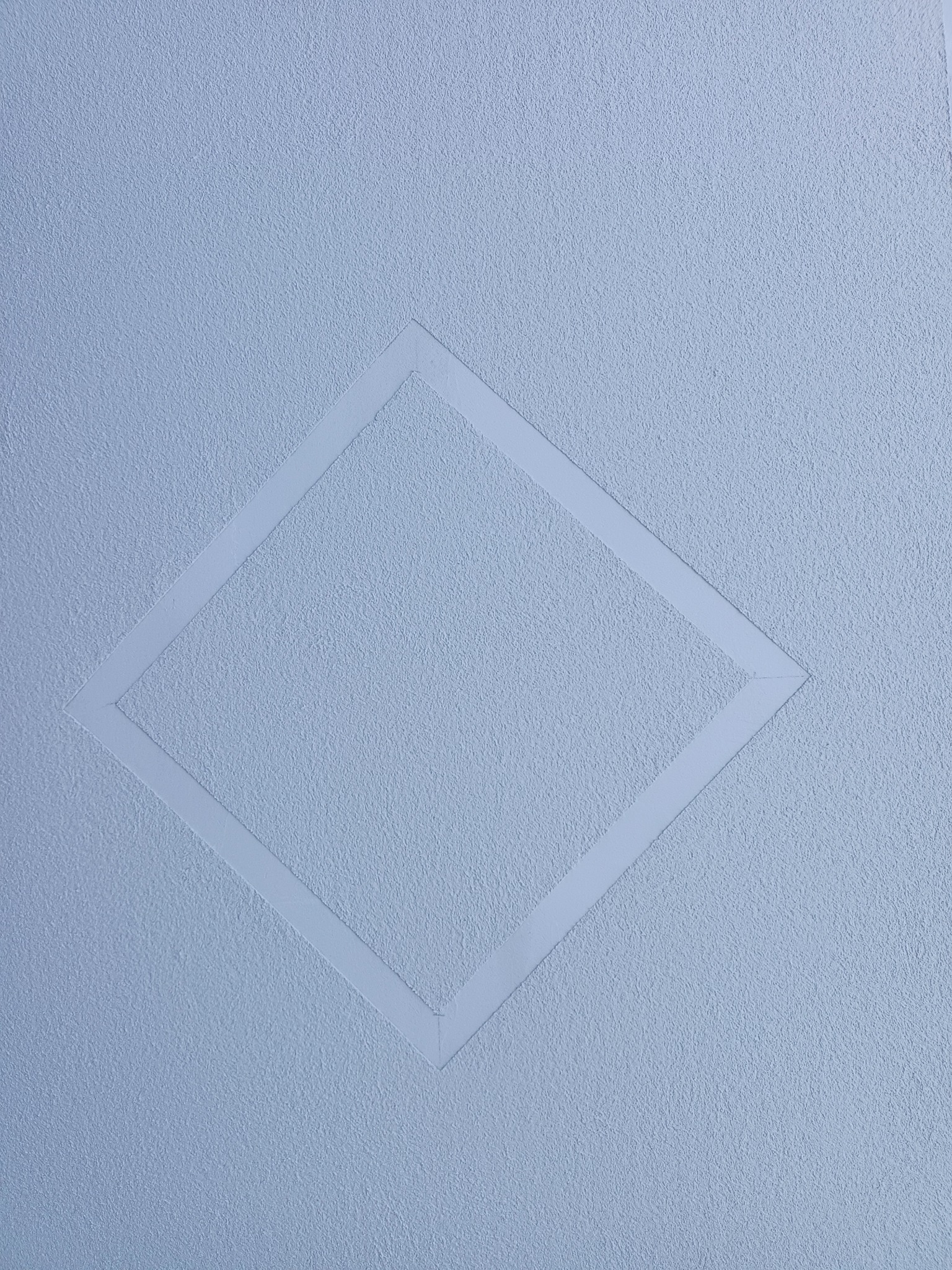 Jasnoniebieska ściana z fakturą i wklęsłym rombem z gładkimi krawędziami, subtelny wzór na powierzchni.