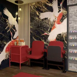 Wnętrze z tapetą w motywie żurawi, czerwonymi fotelami kinowymi, stolikiem z napojami Coca-Cola i oświetleniem wiszącym w stylu industrialnym.