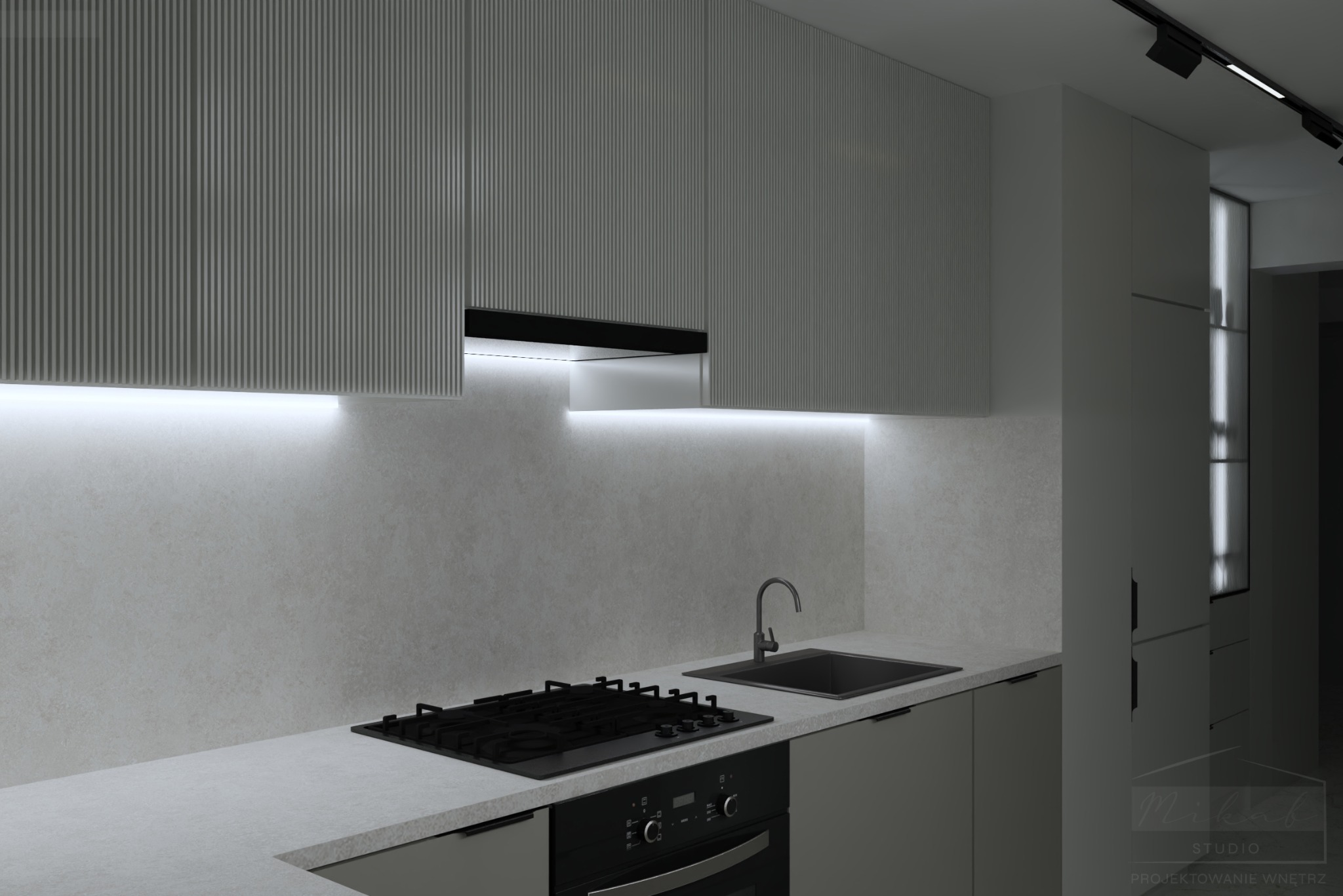 Nowoczesna kuchnia w odcieniach szarości z ryflowanymi frontami szafek górnych, czarną płytą grzewczą i zlewozmywakiem, oświetlona listwami LED pod szafkami.