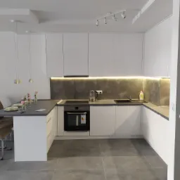 Nowoczesna, minimalistyczna kuchnia z białymi szafkami, szarym blatem i szarą ścianą nad blatem, zintegrowana z wyspą i stołem, oświetlona wiszącymi lampami i listwą LED pod szafkami górnymi.