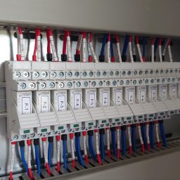 KNM inż. Mateusz Kyrcz - Panel sterowniczy z przekaźnikami Relpol P-1 do P-13, okablowanie w kolorach czerwonym i niebieskim, oznaczone przewody, widok z bliska.