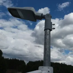 Słup oświetleniowy LED z zamontowaną kamerą monitoringu Dahua na tle błękitnego nieba z obłokami.