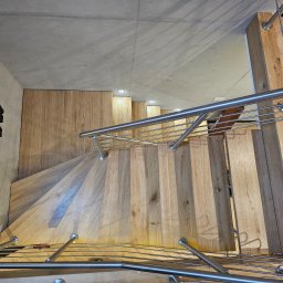 F.H.U. TreeBiel Piotr Bielak - Spiralne schody z jasnego drewna z metalową balustradą, widok z góry, oświetlenie punktowe, dekoracja ścienna w kształcie drzewa, nowoczesny design.