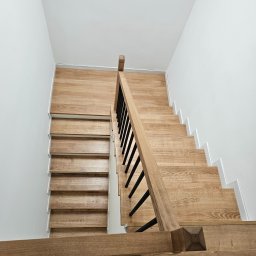 F.H.U. TreeBiel Piotr Bielak - Nowoczesne schody z jasnego drewna z czarnymi balustradami, widok z góry, minimalistyczny design, białe ściany, proste wykończenie.