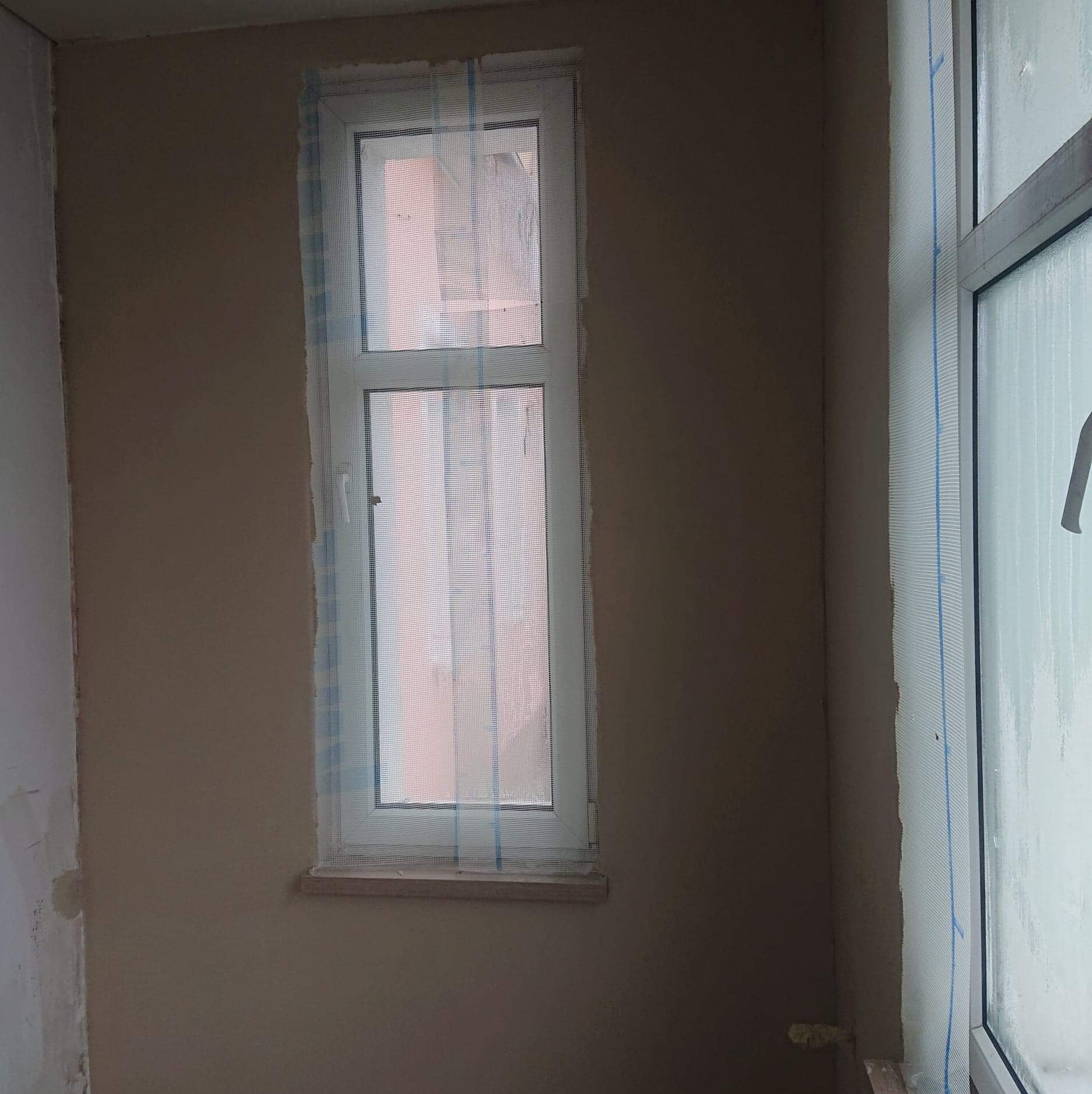 Przygotowanie do malowania: okno zabezpieczone folią malarską, ściana po nałożeniu gładzi, gotowa do malowania.