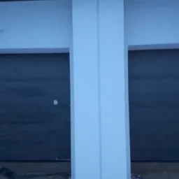 Fragment elewacji z przyklejonymi płytami styropianowymi, zabezpieczonymi taśmą, widoczne nierówności podłoża.