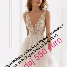 Elegancka panna młoda w koronkowej sukni ślubnej z głębokim dekoltem w kształcie litery V i delikatnymi, tiulowymi ramiączkami, prezentowana na tle białych paneli ściennych, z tekstem promocyjnym...