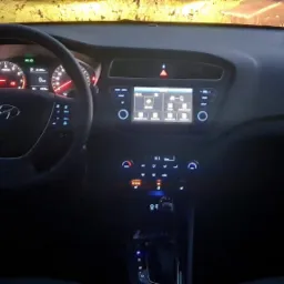 Wnętrze samochodu Hyundai z podświetloną deską rozdzielczą i ekranem dotykowym w ciemnym otoczeniu.