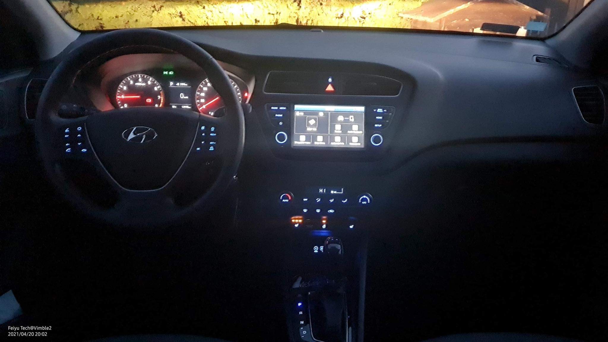 Wnętrze samochodu Hyundai z podświetloną deską rozdzielczą i ekranem dotykowym w ciemnym otoczeniu.