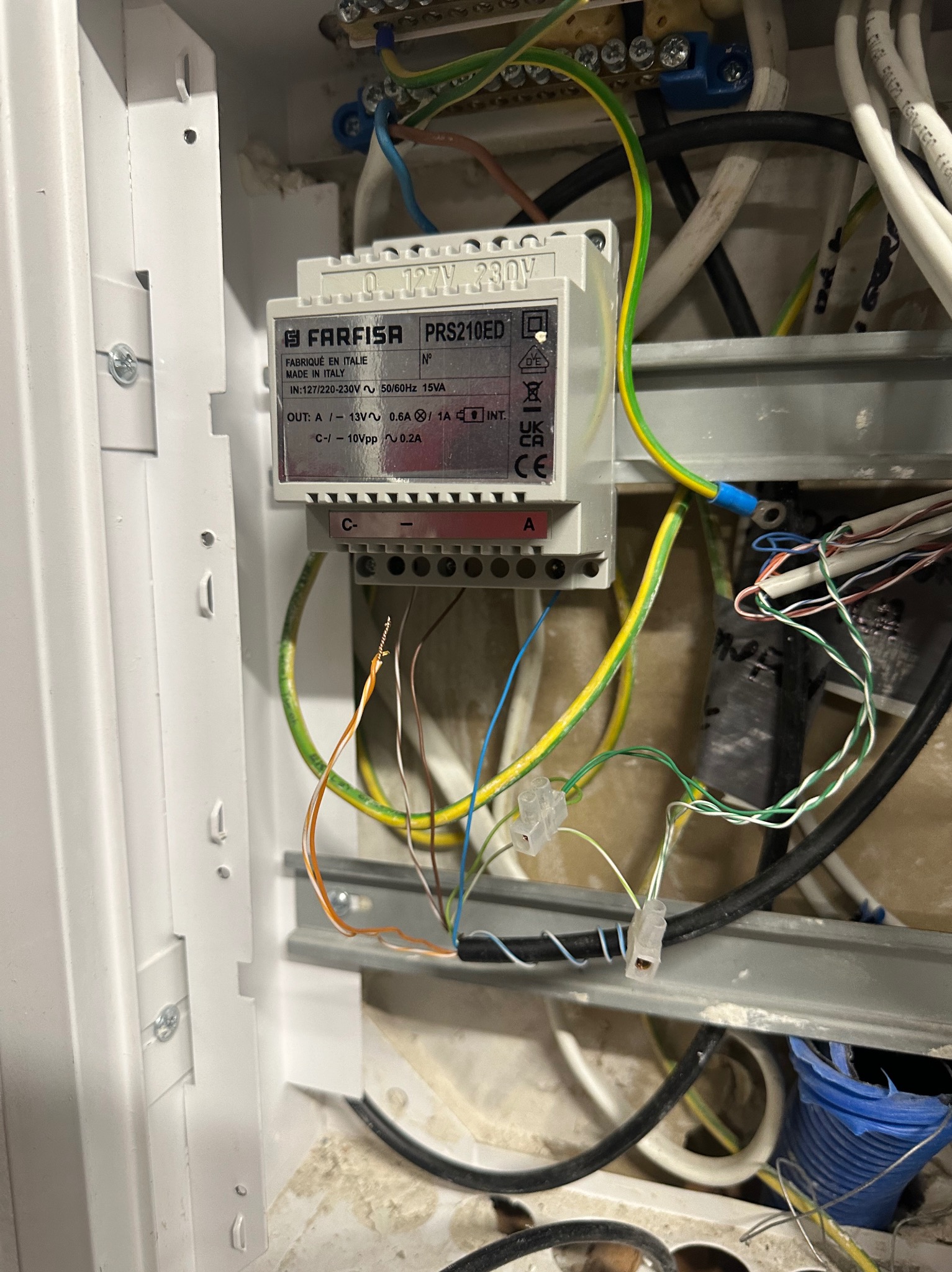 Transformator Farfisa PRS210ED w skrzynce, widoczne przewody i złącza. Instalacja elektryczna w trakcie montażu, z bliska, z elementami instalacji niskonapięciowej.