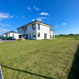 WK SERWIS - Nowo założony trawnik z rolki przed nowoczesnym domem jednorodzinnym w słoneczny dzień, widok zza ogrodzenia.