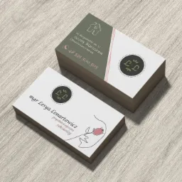 Stos wizytówek psychoterapeuty z Busko-Zdroju, z minimalistycznym logo i ilustracją twarzy z różą, na jasnym drewnianym tle.