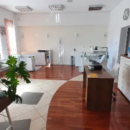 Salon kosmetyczny z lśniącą drewnianą podłogą i stanowiskami do manicure, widok z perspektywy wejścia.