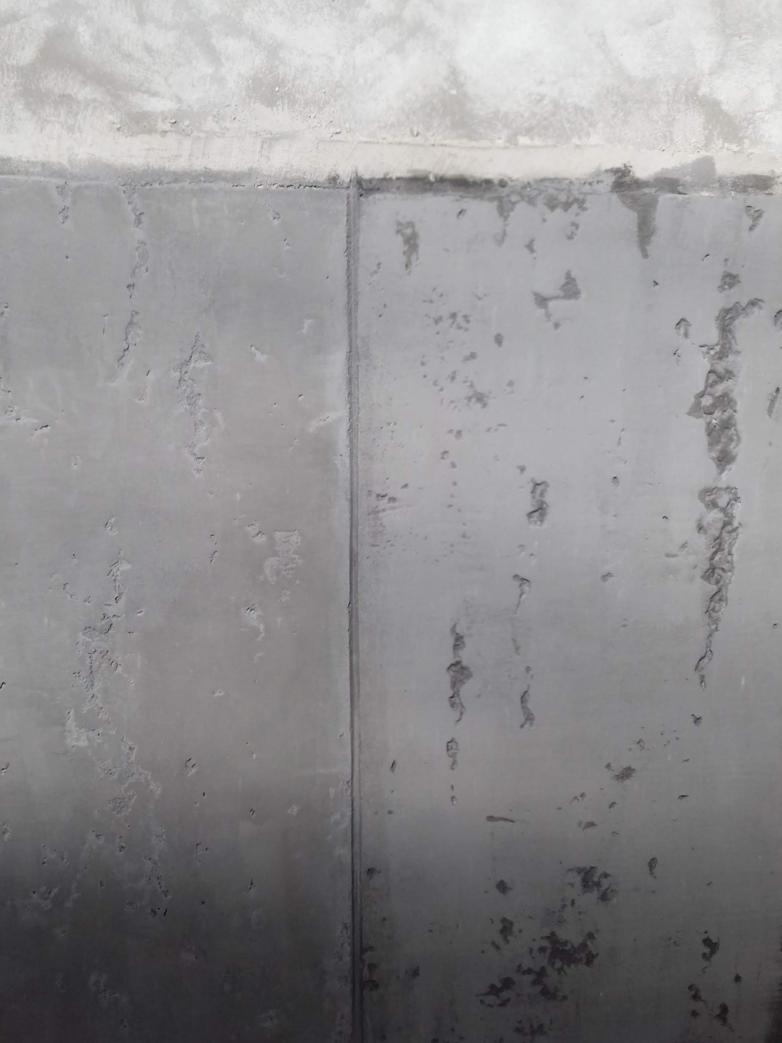 Surowa ściana z betonu komórkowego, przygotowana do dalszych prac wykończeniowych, widoczne ślady po szalunkach i nierówności powierzchni.