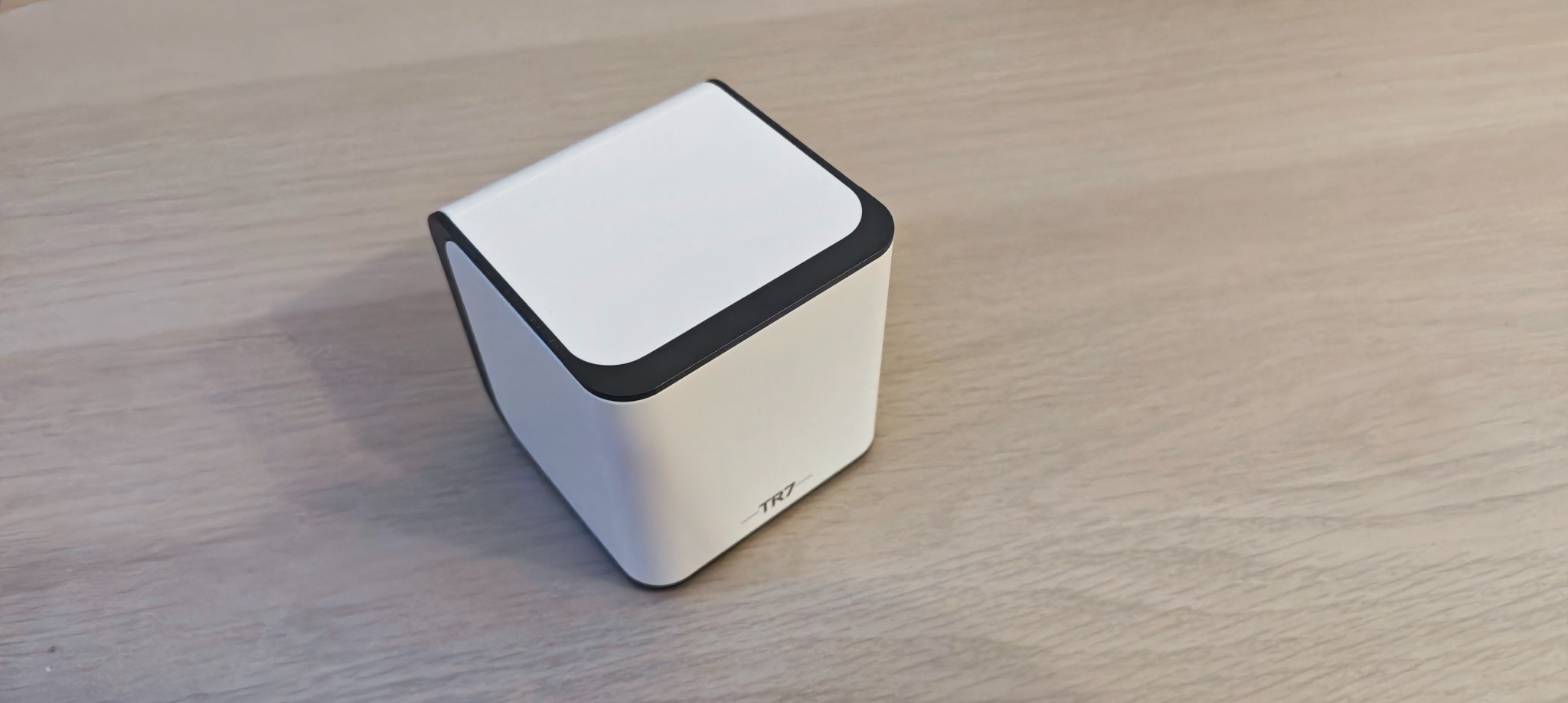 Biała centralka inteligentnego domu TR7, prezentowana przez firmę z Wrocławia, na jasnym drewnianym blacie.
