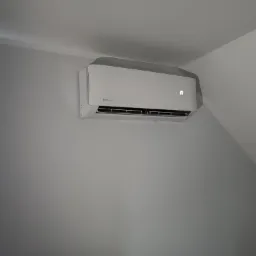 Biały klimatyzator Rotenso zamontowany na ścianie w jasnym pomieszczeniu, widoczny wyświetlacz z literą 'n'.