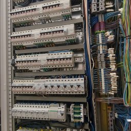 Volt Customs -Maksym Ruban - Rozdzielnica elektryczna z licznymi zabezpieczeniami nadprądowymi, różnicowoprądowymi i przewodami w kolorowej izolacji, zamontowana w metalowej szafie.